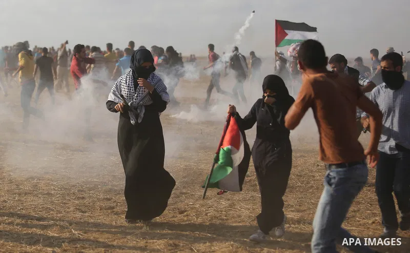 Palestinian protesters run for cover from tear gas canisters fired by Israeli security forces during clashes in a tent city protest where Palestinians demand the right to return to their homeland and against U.S. embassy...