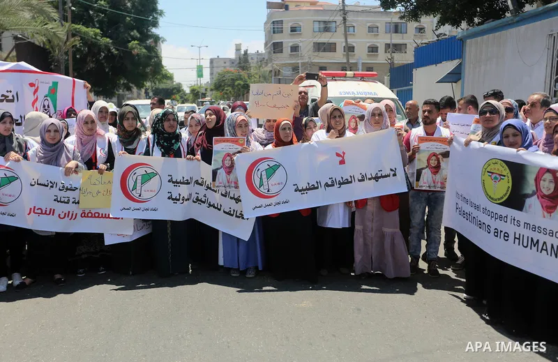 Palestinian medics hold posters depicting nurse Razan Al-Najar who was shot dead by Israeli soldiers as she a bid to reach a casualty during clashes between Palestinian protesters and Israeli troops at Israel-Gaza border...