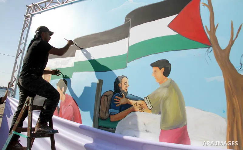 A Palestinian artist paints a mural at Gaza seaport, on June 4, 2018. Photo by Mahmoud Ajour