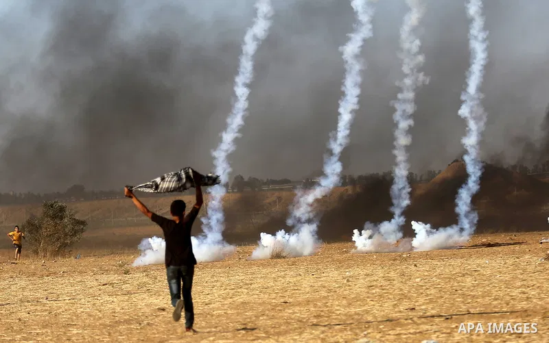 Palestinian protesters run for cover from tear gas canisters fired by Israeli security forces during clashes in a tent city protest where Palestinians demand the right to return to their homeland and against U.S. embassy...