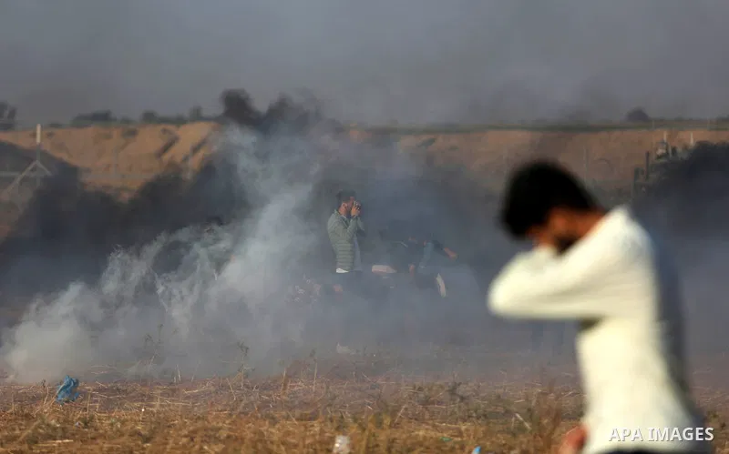 Palestinian protesters run for cover from tear gas canisters fired by Israeli security forces during clashes in a tent city protest where Palestinians demand the right to return to their homeland and against U.S. embassy...