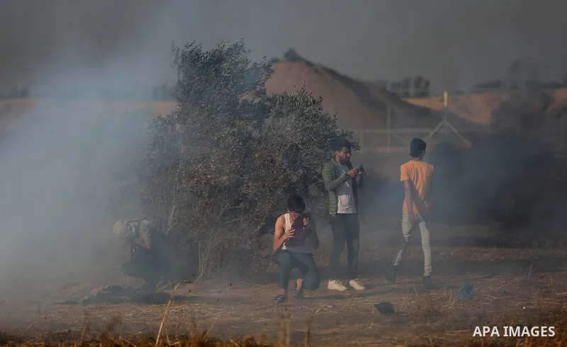 Palestinian protesters run for cover from tear gas canisters fired by Israeli security forces during clashes in a tent city protest where Palestinians demand the right to return to their homeland and against U.S. embassy...