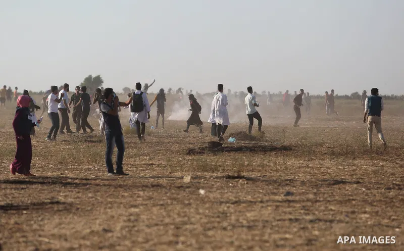 Palestinian protesters run for cover from tear gas canisters fired by Israeli security forces during clashes in a tent city protest where Palestinians demand the right to return to their homeland and against U.S. embassy...
