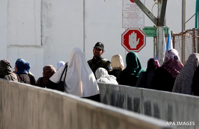Palestinians make their way through an Israeli checkpoint along Israel's controversial separation barrier to attend the last Friday prayer of the holy fasting month of Ramadan in Jerusalem's Al-Aqsa mosque, in Bethlehem...