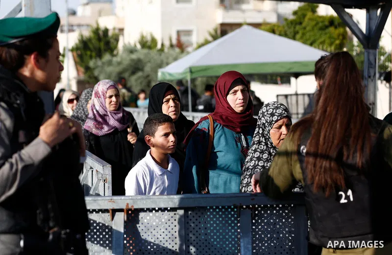 Palestinians make their way through an Israeli checkpoint along Israel's controversial separation barrier to attend the last Friday prayer of the holy fasting month of Ramadan in Jerusalem's Al-Aqsa mosque, in Bethlehem...