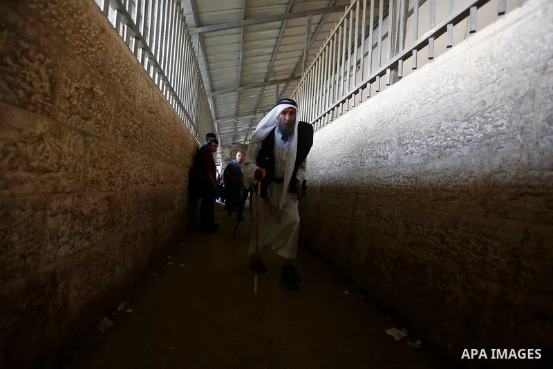 Palestinians make their way through an Israeli checkpoint along Israel's controversial separation barrier to attend the last Friday prayer of the holy fasting month of Ramadan in Jerusalem's Al-Aqsa mosque, in Bethlehem...