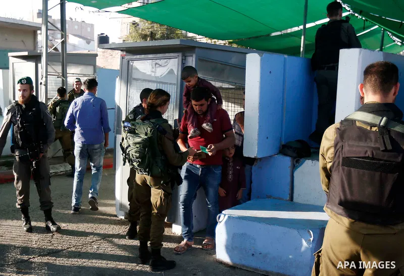 Palestinians make their way through an Israeli checkpoint along Israel's controversial separation barrier to attend the last Friday prayer of the holy fasting month of Ramadan in Jerusalem's Al-Aqsa mosque, in Bethlehem...