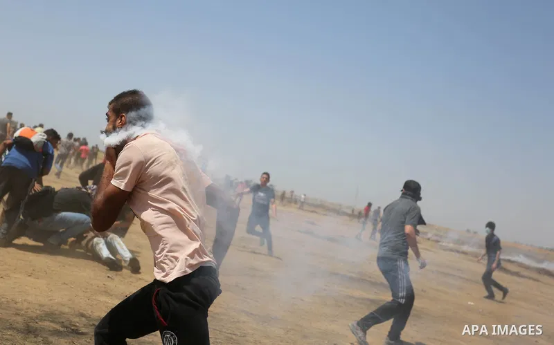 A wounded Palestinian protester reacts as he is hit in the face with a tear gas canister fired by Israeli troops during a protest marking al-Quds Day, (Jerusalem Day), at the Israel-Gaza border in Khan Younis in the sout...
