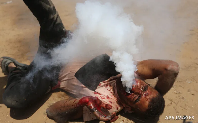 A wounded Palestinian protester reacts as he is hit in the face with a tear gas canister fired by Israeli troops during a protest marking al-Quds Day, (Jerusalem Day), at the Israel-Gaza border in Khan Younis in the sout...