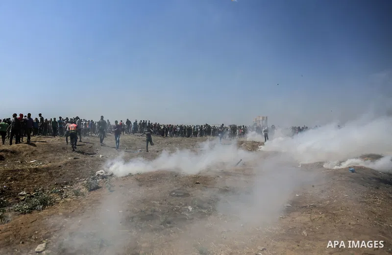Palestinian protesters run for cover from tear gas canisters fired by Israeli security forces during a protest marking al-Quds Day, (Jerusalem Day), at the Israel-Gaza border in east of Gaza city, on June 8, 2018. Photo...