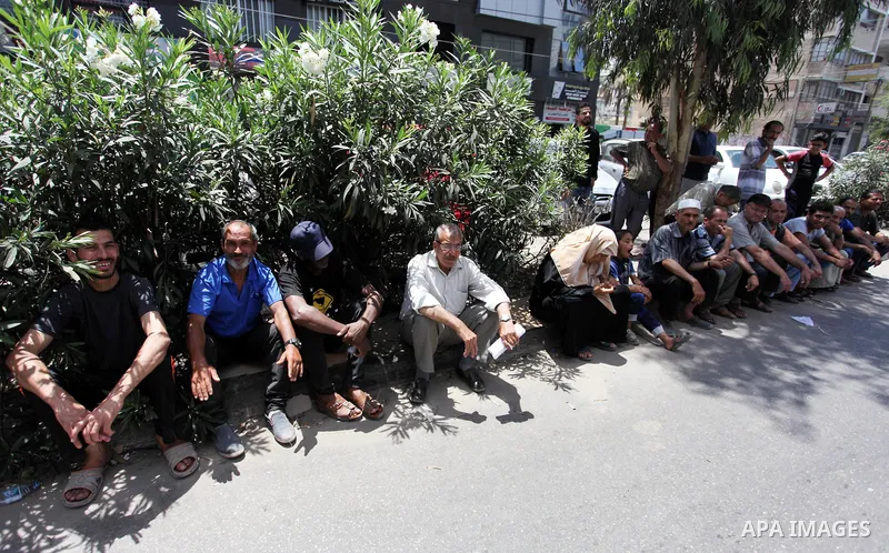 Palestinians of Social Affairs wait in front of Bank of Palestine to withdraw their financial aid in Gaza City on June 10, 2018. Photo by Mahmoud Ajour
