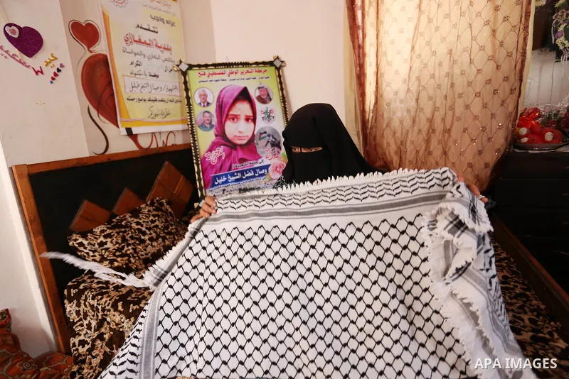 The mother of Palestinian Wesal Sheikh Khalil, 15, who was shot dead by Israeli troops during clashes at Israel-Gaza border carries stuffs belongs to her daughter at their home at al-Maghazi camp in the center of Gaza St...