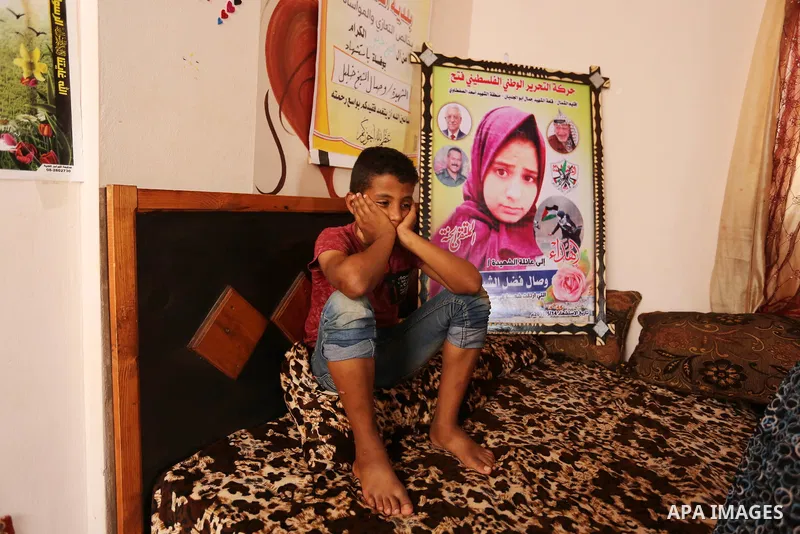 The brother of Palestinian Wesal Sheikh Khalil, 15, who was shot dead by Israeli troops during clashes at Israel-Gaza border, sits next to a poster depicting her picture at their home at al-Maghazi camp in the center of...