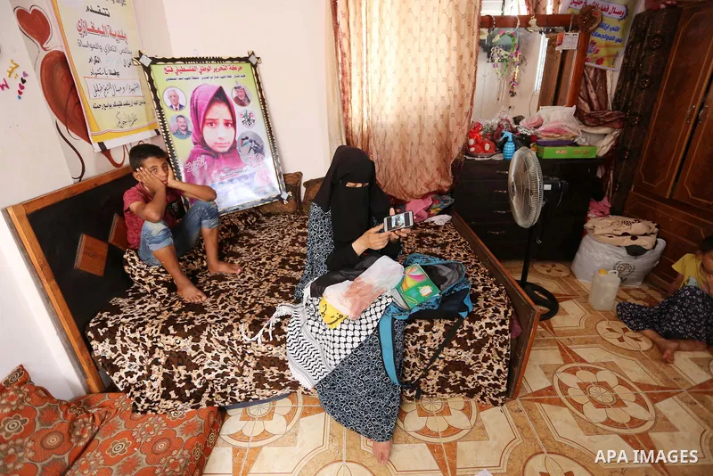 The mother of Palestinian Wesal Sheikh Khalil, 15, who was shot dead by Israeli troops during clashes at Israel-Gaza border carries stuffs belongs to her daughter at their home at al-Maghazi camp in the center of Gaza St...