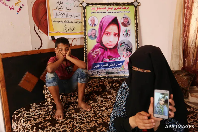 The mother of Palestinian Wesal Sheikh Khalil, 15, who was shot dead by Israeli troops during clashes at Israel-Gaza border holds a mobile phone and showing the picture of her daughter at their home at al-Maghazi camp in...