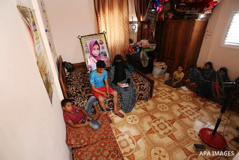 The family of Palestinian Wesal Sheikh Khalil, 15, who was shot dead by Israeli troops during clashes at Israel-Gaza border, sit next to a poster depicting her picture at their home at al-Maghazi camp in the center of Ga...
