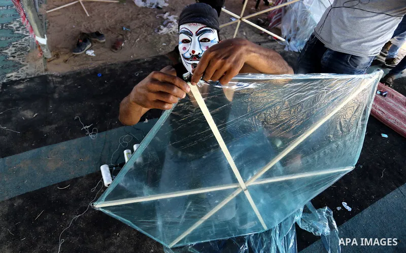 Palestinian protesters prepare kites loaded with flammable material to be flown towards Israel, at the Israel-Gaza border in al-Bureij in the center of Gaza Strip on June 11, 2018. Photo by Ashraf Amra