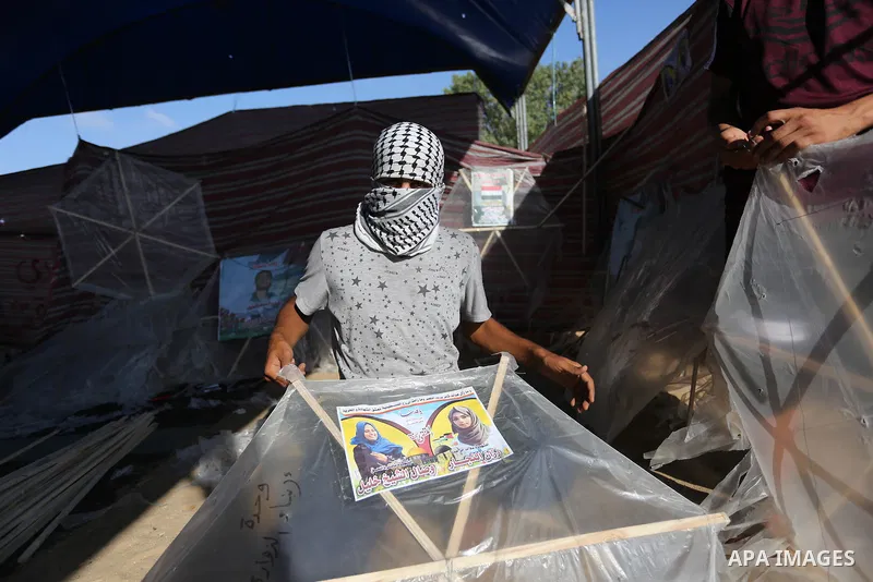 Palestinian protesters prepare kites loaded with flammable material to be flown towards Israel, at the Israel-Gaza border in al-Bureij in the center of Gaza Strip on June 11, 2018. Photo by Ashraf Amra