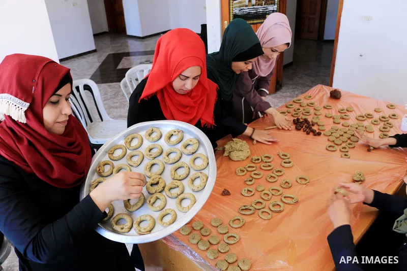 Palestinian women prepare traditional date-filled mini cakes to sell for customers a few days ahead of Eid al-Fitr holiday in Dair Al Balah, in the center of Gaza Strip on June 12, 2018. Eid al-Fitr marks the end of Musl...