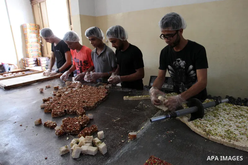 Palestinians prepare sweet known in Arabic as "Halkoum" in a store to be sold ahead of the Eid al-Fitr holiday in Gaza city on June 13, 2018. Eid al-Fitr marks the end of Muslim's holy fasting month of Ramadan when faith...