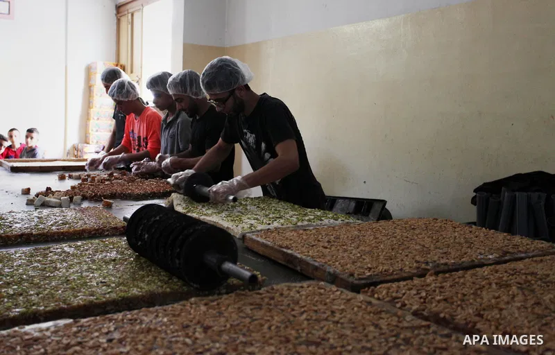 Palestinians prepare sweet known in Arabic as "Halkoum" in a store to be sold ahead of the Eid al-Fitr holiday in Gaza city on June 13, 2018. Eid al-Fitr marks the end of Muslim's holy fasting month of Ramadan when faith...