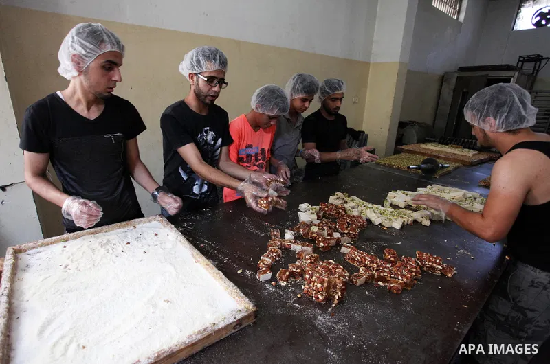 Palestinians prepare sweet known in Arabic as "Halkoum" in a store to be sold ahead of the Eid al-Fitr holiday in Gaza city on June 13, 2018. Eid al-Fitr marks the end of Muslim's holy fasting month of Ramadan when faith...