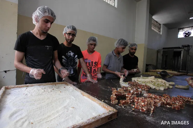 Palestinians prepare sweet known in Arabic as "Halkoum" in a store to be sold ahead of the Eid al-Fitr holiday in Gaza city on June 13, 2018. Eid al-Fitr marks the end of Muslim's holy fasting month of Ramadan when faith...