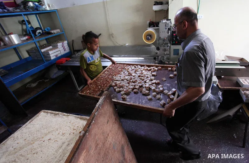 Palestinians prepare sweet known in Arabic as "Halkoum" in a store to be sold ahead of the Eid al-Fitr holiday in Gaza city on June 13, 2018. Eid al-Fitr marks the end of Muslim's holy fasting month of Ramadan when faith...