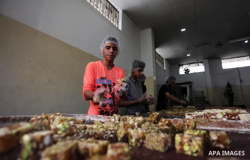 Palestinians prepare sweet known in Arabic as "Halkoum" in a store to be sold ahead of the Eid al-Fitr holiday in Gaza city on June 13, 2018. Eid al-Fitr marks the end of Muslim's holy fasting month of Ramadan when faith...