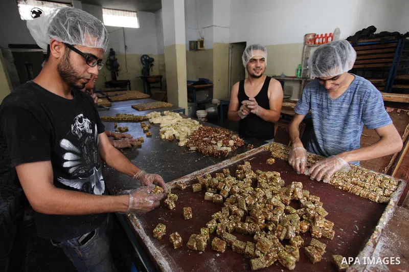 Palestinians prepare sweet known in Arabic as "Halkoum" in a store to be sold ahead of the Eid al-Fitr holiday in Gaza city on June 13, 2018. Eid al-Fitr marks the end of Muslim's holy fasting month of Ramadan when faith...