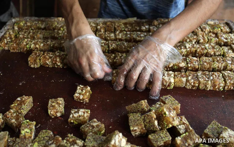 Palestinians prepare sweet known in Arabic as "Halkoum" in a store to be sold ahead of the Eid al-Fitr holiday in Gaza city on June 13, 2018. Eid al-Fitr marks the end of Muslim's holy fasting month of Ramadan when faith...