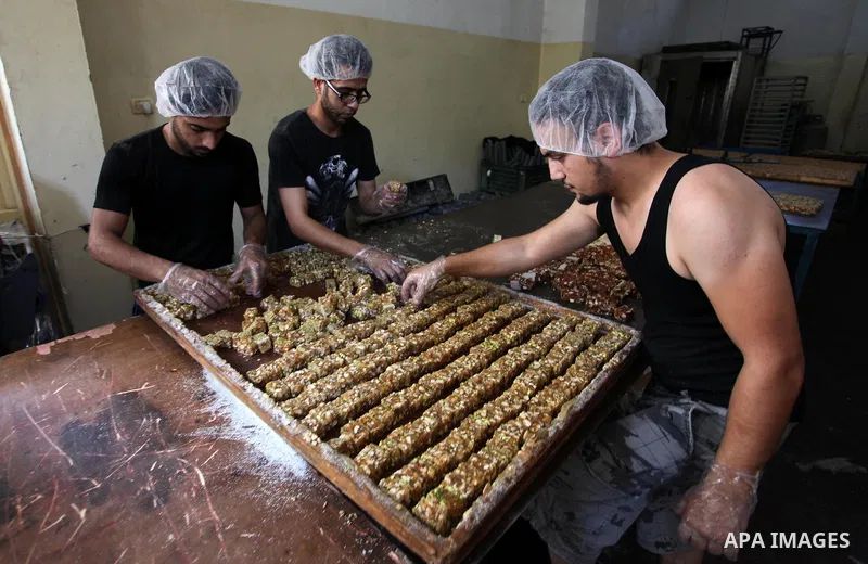 Palestinians prepare sweet known in Arabic as "Halkoum" in a store to be sold ahead of the Eid al-Fitr holiday in Gaza city on June 13, 2018. Eid al-Fitr marks the end of Muslim's holy fasting month of Ramadan when faith...