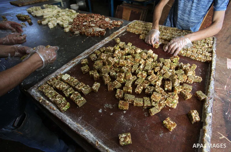 Palestinians prepare sweet known in Arabic as "Halkoum" in a store to be sold ahead of the Eid al-Fitr holiday in Gaza city on June 13, 2018. Eid al-Fitr marks the end of Muslim's holy fasting month of Ramadan when faith...