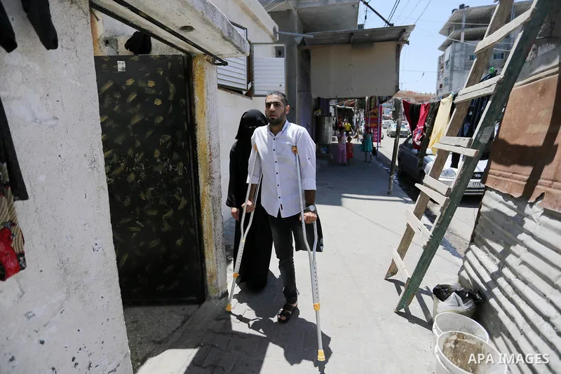 Palestinian disabled Mohammed Al Akhras, 32, who lost his leg by Israeli troops during clashes at Gaza-Israel border uses his crutch to walk at his home before he going to market ahead of Eid al-Fitr holiday, in Rafah in...