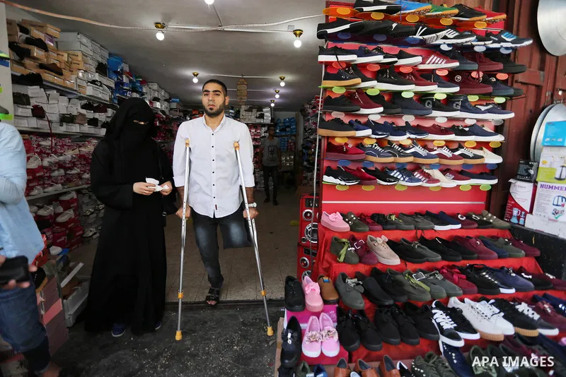 Palestinian disabled Mohammed Al Akhras, 32, who lost his leg by Israeli troops during clashes at Gaza-Israel border uses his crutch to walk at market as he shopping ahead of Eid al-Fitr holiday, in Rafah in the southern...
