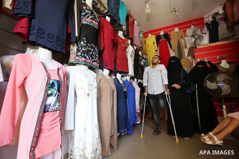 Palestinian disabled Mohammed Al Akhras, 32, who lost his leg by Israeli troops during clashes at Gaza-Israel border uses his crutch to walk at market as he shopping ahead of Eid al-Fitr holiday, in Rafah in the southern...