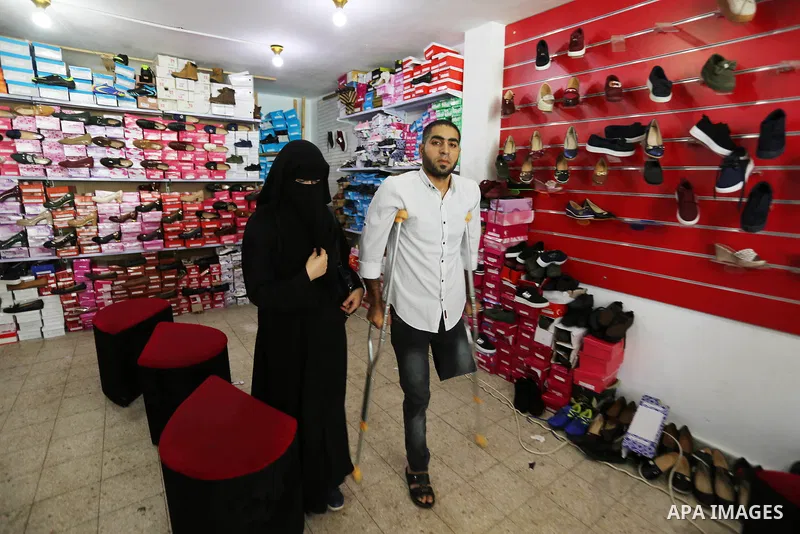 Palestinian disabled Mohammed Al Akhras, 32, who lost his leg by Israeli troops during clashes at Gaza-Israel border uses his crutch to walk at market as he shopping ahead of Eid al-Fitr holiday, in Rafah in the southern...