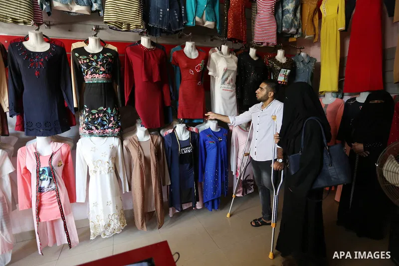 Palestinian disabled Mohammed Al Akhras, 32, who lost his leg by Israeli troops during clashes at Gaza-Israel border uses his crutch to walk at market as he shopping ahead of Eid al-Fitr holiday, in Rafah in the southern...