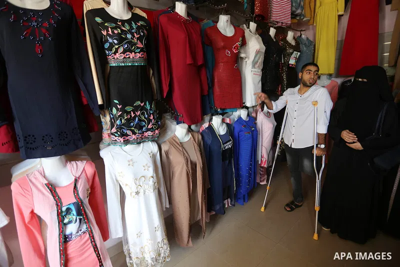 Palestinian disabled Mohammed Al Akhras, 32, who lost his leg by Israeli troops during clashes at Gaza-Israel border uses his crutch to walk at market as he shopping ahead of Eid al-Fitr holiday, in Rafah in the southern...