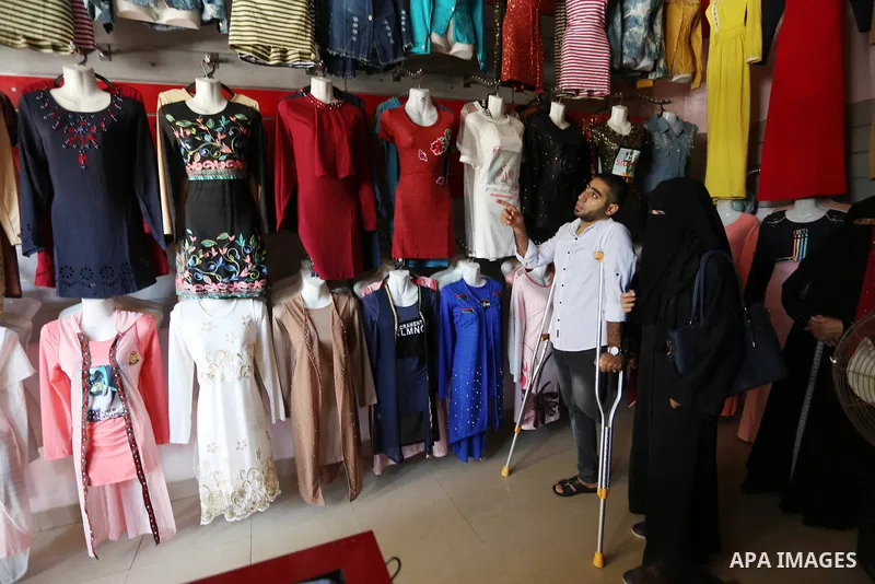 Palestinian disabled Mohammed Al Akhras, 32, who lost his leg by Israeli troops during clashes at Gaza-Israel border uses his crutch to walk at market as he shopping ahead of Eid al-Fitr holiday, in Rafah in the southern...