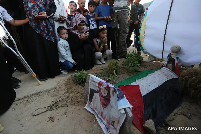 Relatives of nurse Razan Al-Najar, who was shot dead by Israeli soldiers clashes at Israel-Gaza border, visit her grave at a cemetery on the first day of Eid al-Fitr, in Khan Younis in the southern Gaza strip on June 15,...