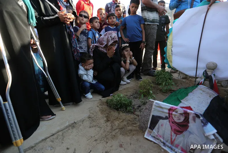 Relatives of nurse Razan Al-Najar, who was shot dead by Israeli soldiers clashes at Israel-Gaza border, visit her grave at a cemetery on the first day of Eid al-Fitr, in Khan Younis in the southern Gaza strip on June 15,...