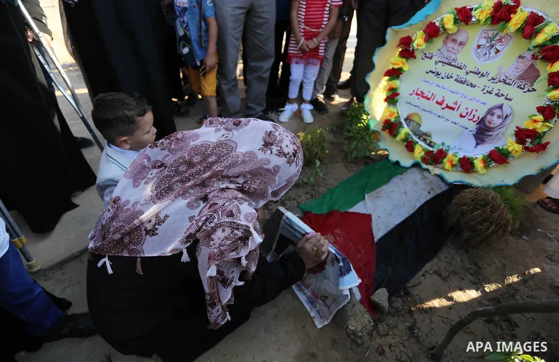 Relatives of nurse Razan Al-Najar, who was shot dead by Israeli soldiers clashes at Israel-Gaza border, visit her grave at a cemetery on the first day of Eid al-Fitr, in Khan Younis in the southern Gaza strip on June 15,...