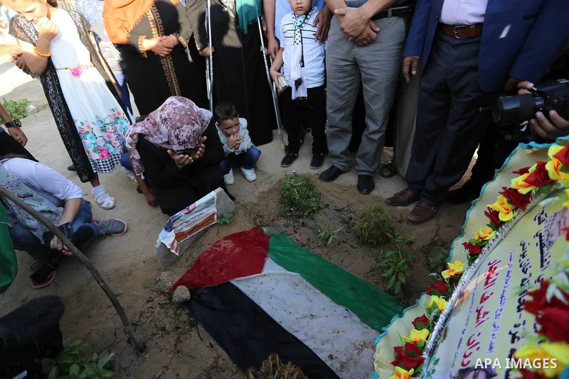Relatives of nurse Razan Al-Najar, who was shot dead by Israeli soldiers clashes at Israel-Gaza border, visit her grave at a cemetery on the first day of Eid al-Fitr, in Khan Younis in the southern Gaza strip on June 15,...