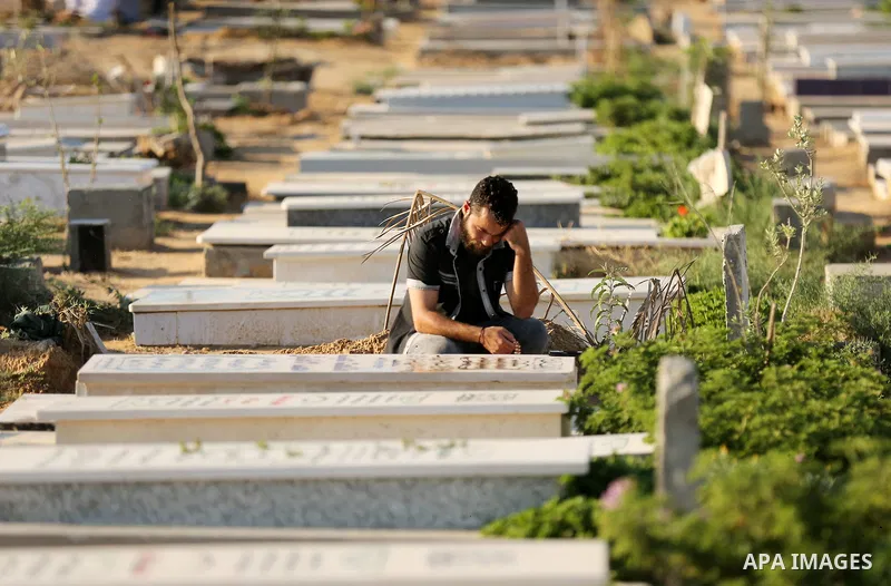 Palestinians visit the grave of their relative at a cemetery on the first day of Eid al-Fitr in Gaza city on June 15, 2018. Eid al-Fitr marks the end of Muslim's holy fasting month of Ramadan when faithfuls abstain from...