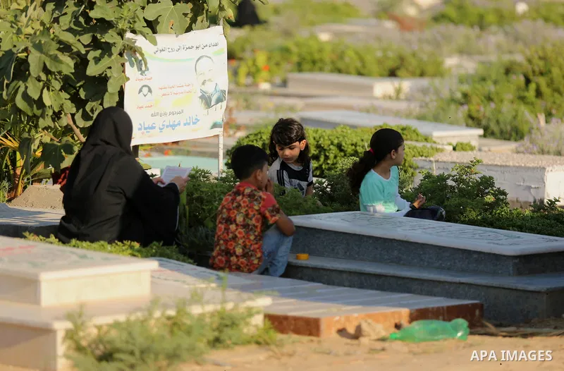 Palestinians visit the grave of their relative at a cemetery on the first day of Eid al-Fitr in Gaza city on June 15, 2018. Eid al-Fitr marks the end of Muslim's holy fasting month of Ramadan when faithfuls abstain from...