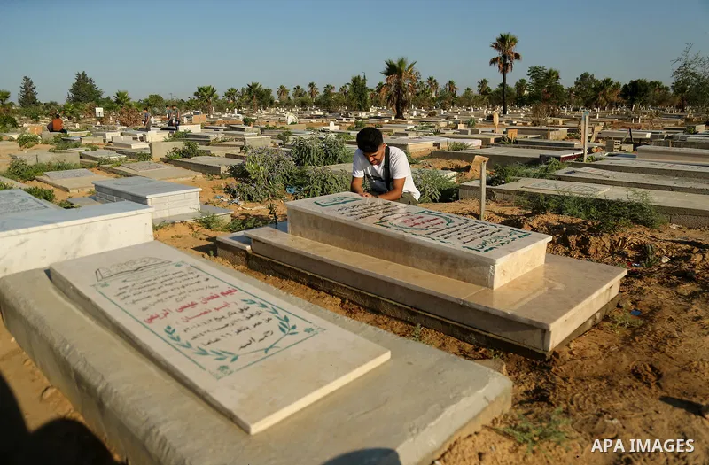 Palestinians visit the grave of their relative at a cemetery on the first day of Eid al-Fitr in Gaza city on June 15, 2018. Eid al-Fitr marks the end of Muslim's holy fasting month of Ramadan when faithfuls abstain from...