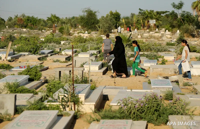 Palestinians visit the grave of their relative at a cemetery on the first day of Eid al-Fitr in Gaza city on June 15, 2018. Eid al-Fitr marks the end of Muslim's holy fasting month of Ramadan when faithfuls abstain from...