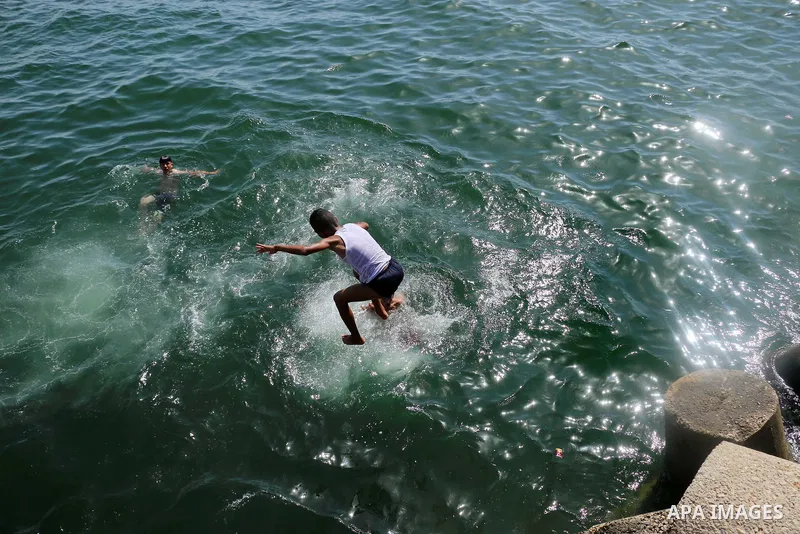 A Palestinian youth jumps into the Mediterranean Sea at the Gaza seaport in Gaza City on the third day of Eid al-Fitr holiday which marks the end of the Muslim holy month of Ramadan, on June 17, 2018. Photo by Mahmoud Kh...