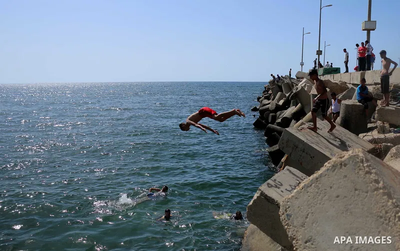 A Palestinian youth jumps into the Mediterranean Sea at the Gaza seaport in Gaza City on the third day of Eid al-Fitr holiday which marks the end of the Muslim holy month of Ramadan, on June 17, 2018. Photo by Mahmoud Kh...